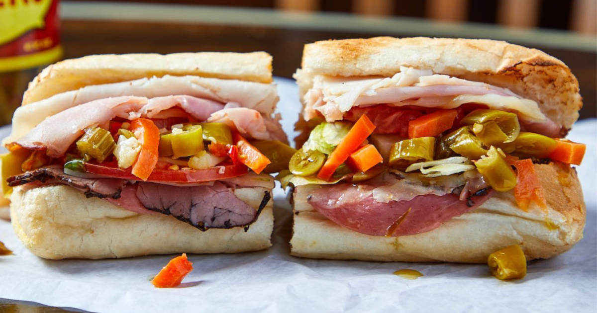 sandwich with meat and veggies cut in half on parchment paper