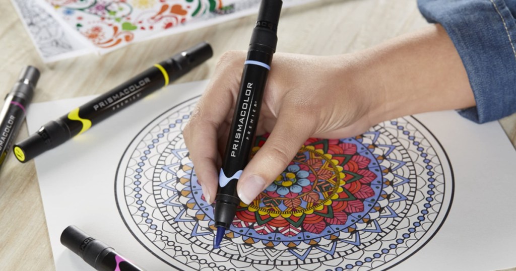 woman's hand using a prismacolor marker to color a mandala adult coloring page