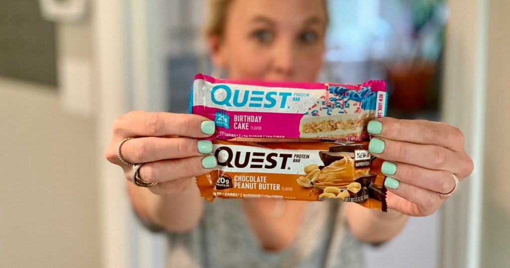 woman holding up two Quest bars