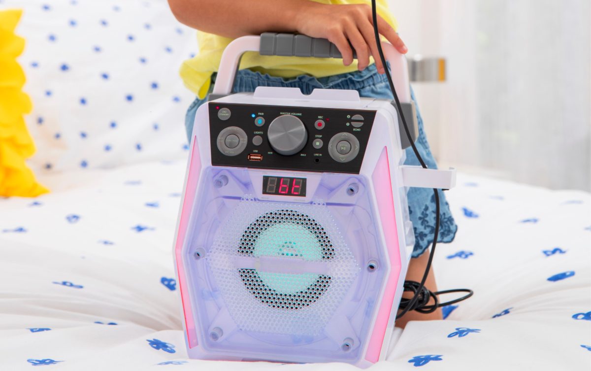 girl using purple glow karaoke machine on bed