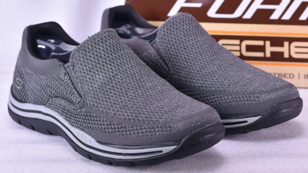 men's gray slip-on shoes in front of shoe box