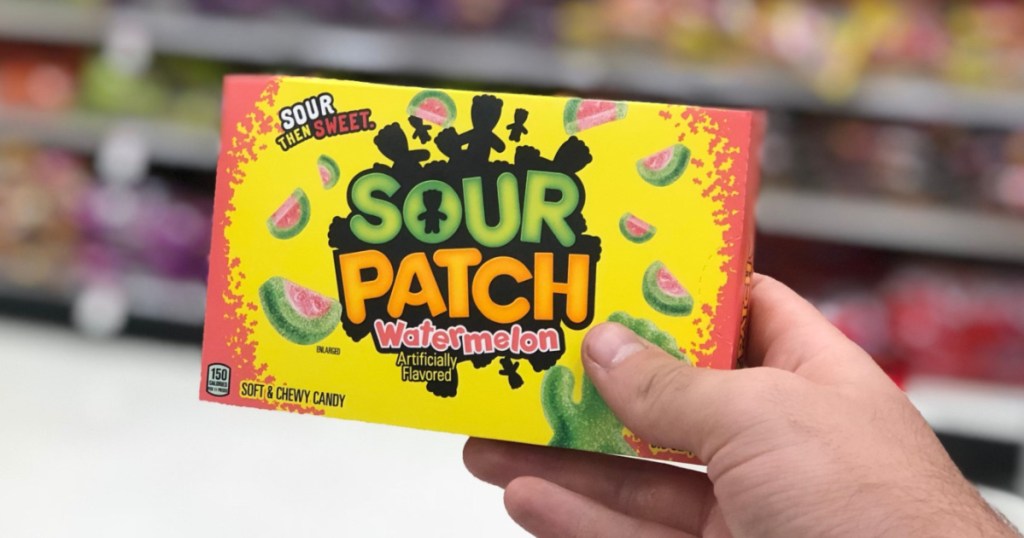 hand holding box of sour candy in store aisle