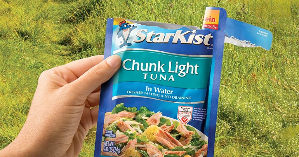 person holding an open packet of starkist tuna