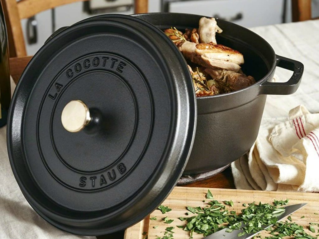 Black cast iron cocette with chicken quarters and herbs inside