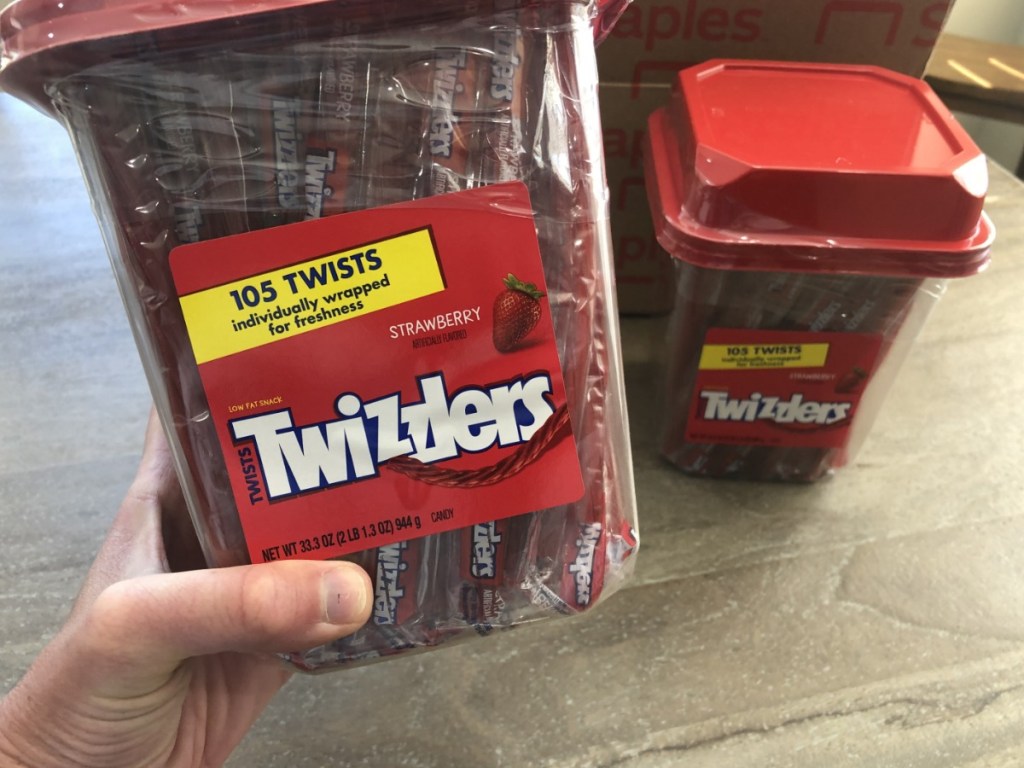 Person holding large tub of Strawberry Twizzlers 