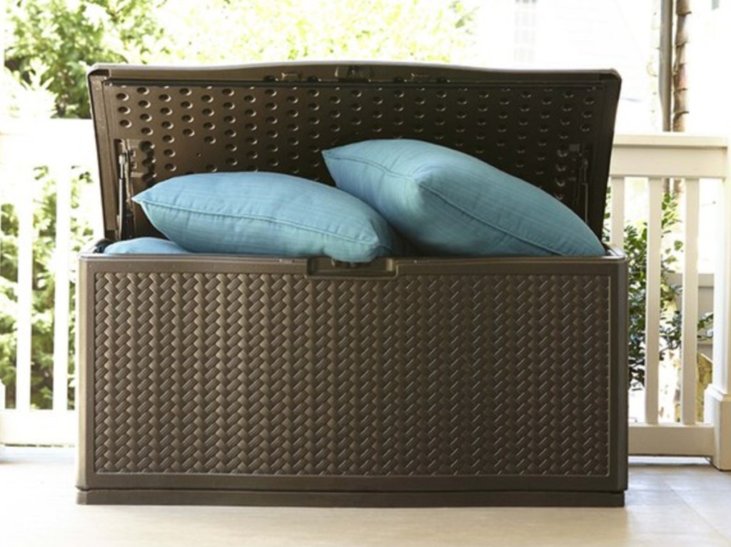 brown deck box on deck filled with blue pillows