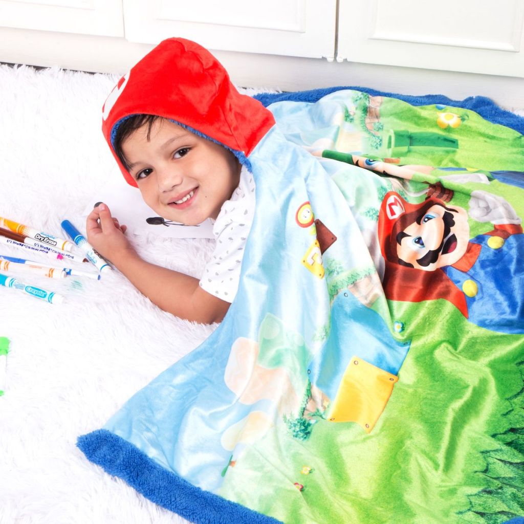 boy wearing Super Mario Snuggle Wrap Hoodie Blanket laying on the floor