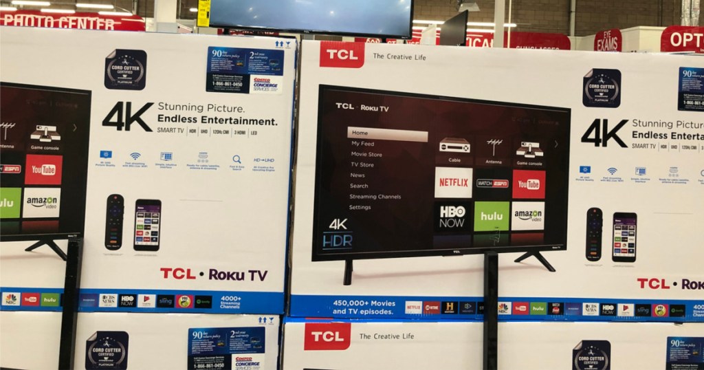 smart tv boxes stacked in store below hanging tv