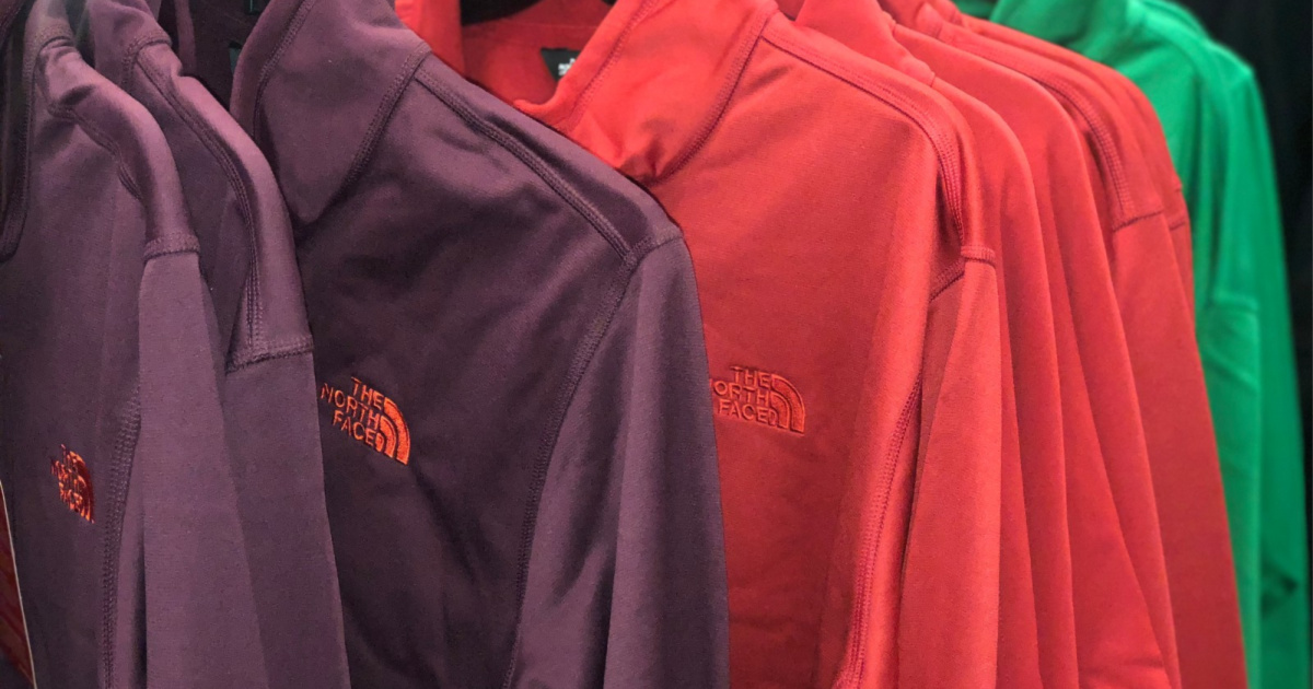 purple, red, and green pullovers hanging on rack in store