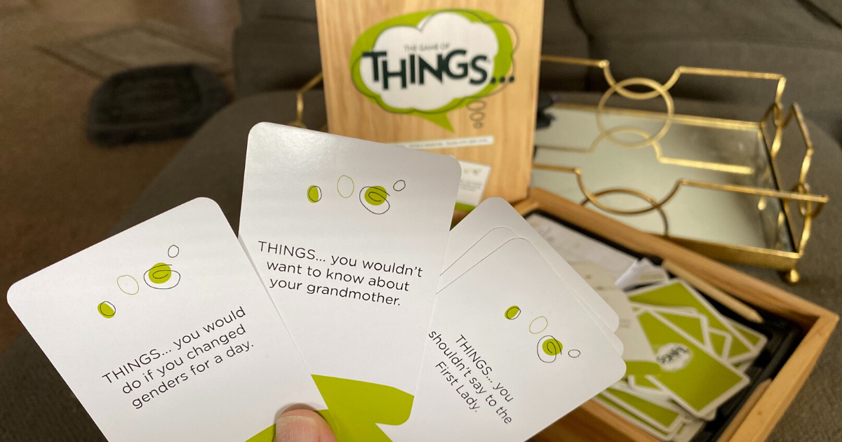 Hand holding cards from The Game of Things in living room