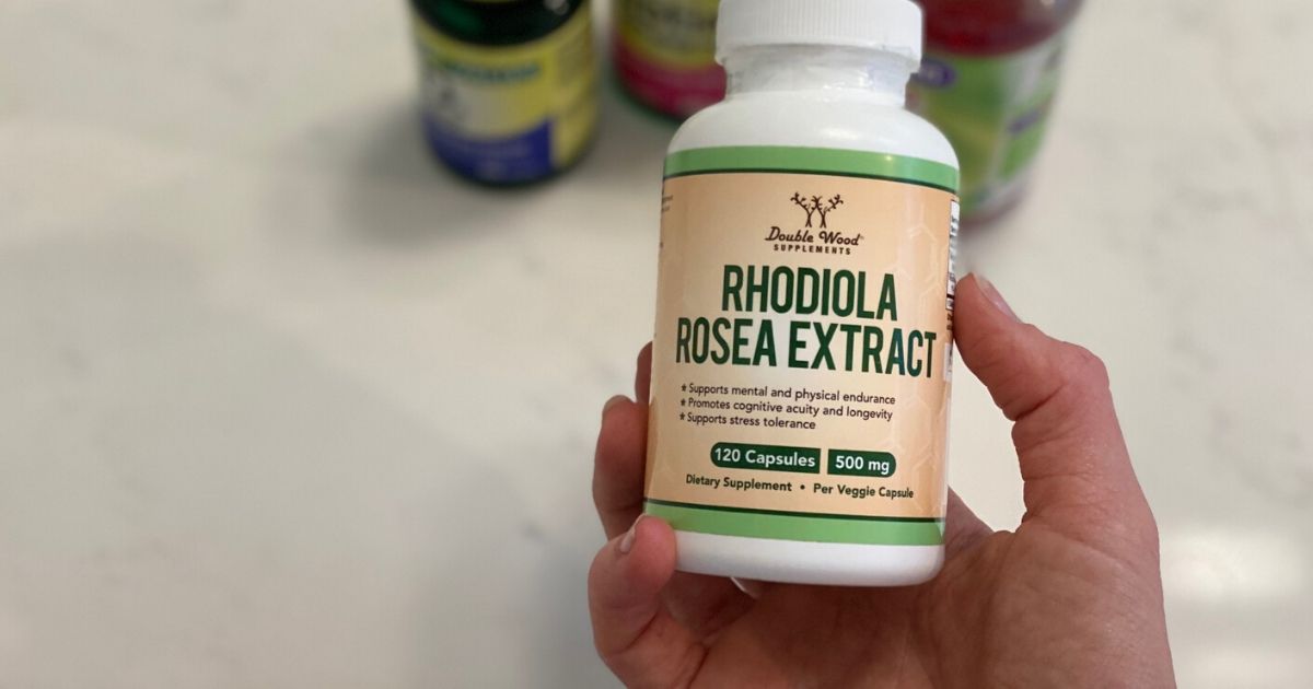 Hand holding a bottle of Rhodiola rosea supplement in bathroom