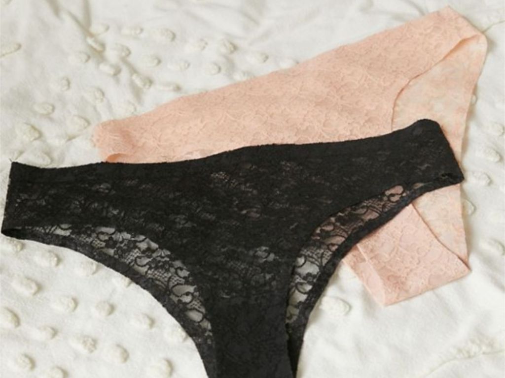 black pair and blush pink pair of lace panties from urban outfitters on white quilt