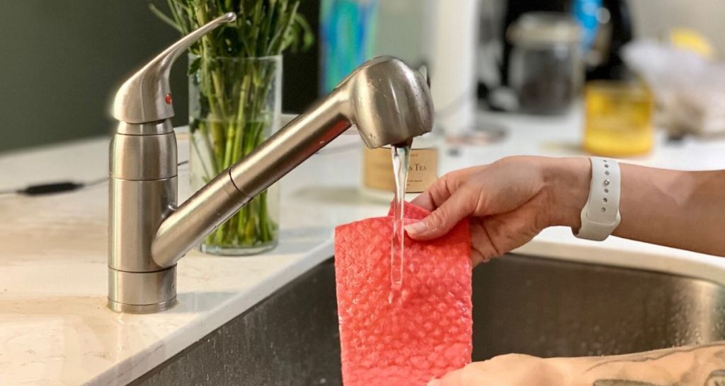 Hands washing a Swedish Dishcloth over the kitchen sink