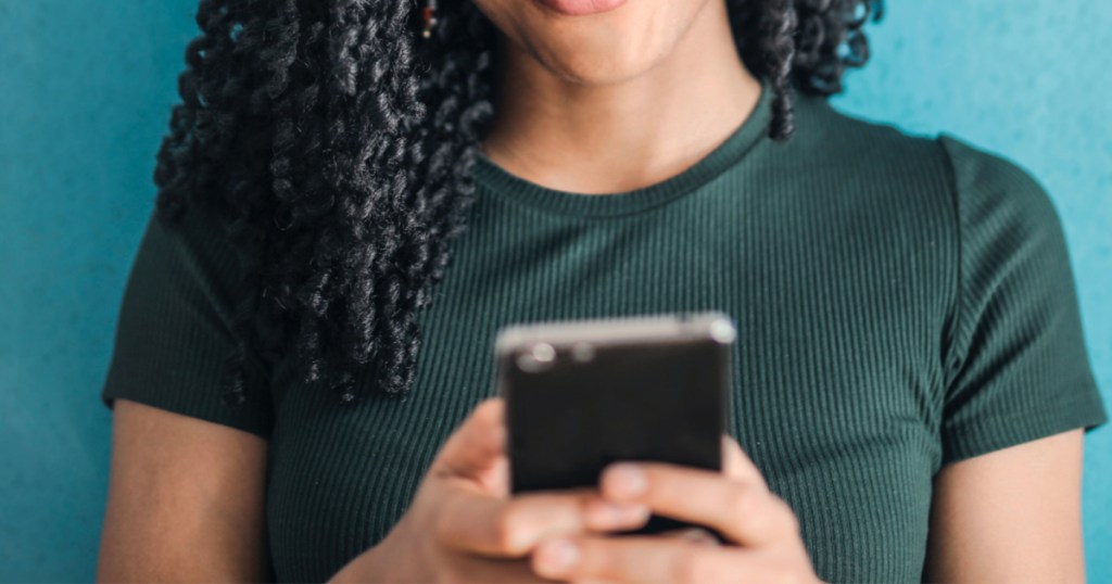 woman in green shirt using black cell phone