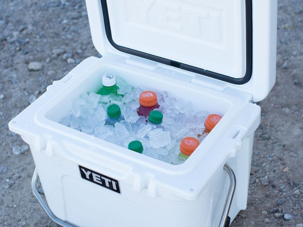 large white cooler on ground outside filled with ice and various bottles drinks