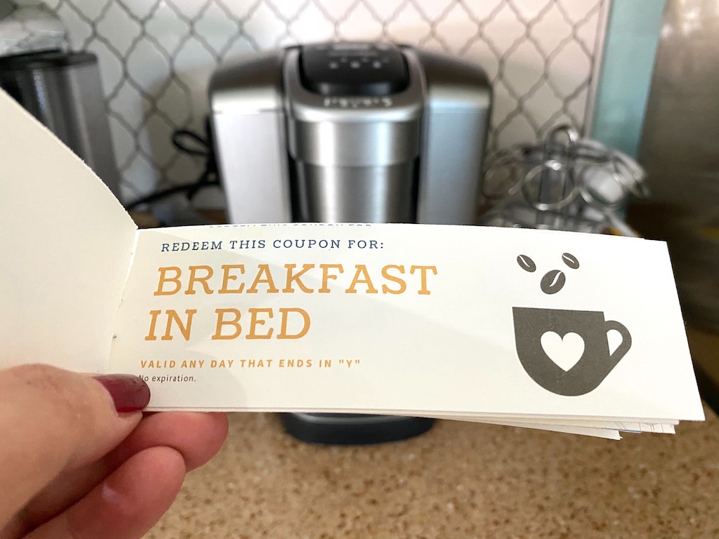 holding Breakfast in Bed Mother's Day coupon with Keurig in background 