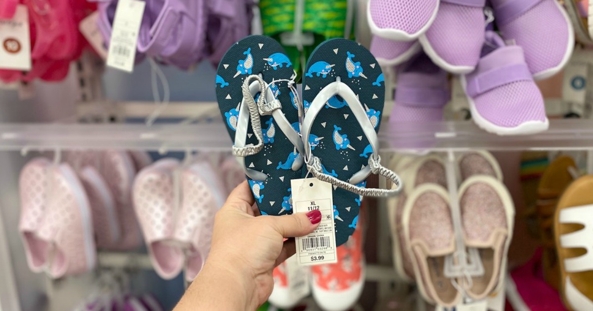 hand holding pair of kids flip flops in Target store