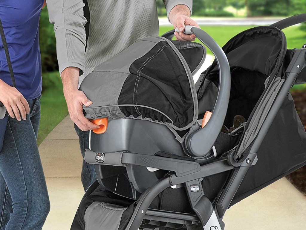 man and woman putting a carseat on the top of a stroller