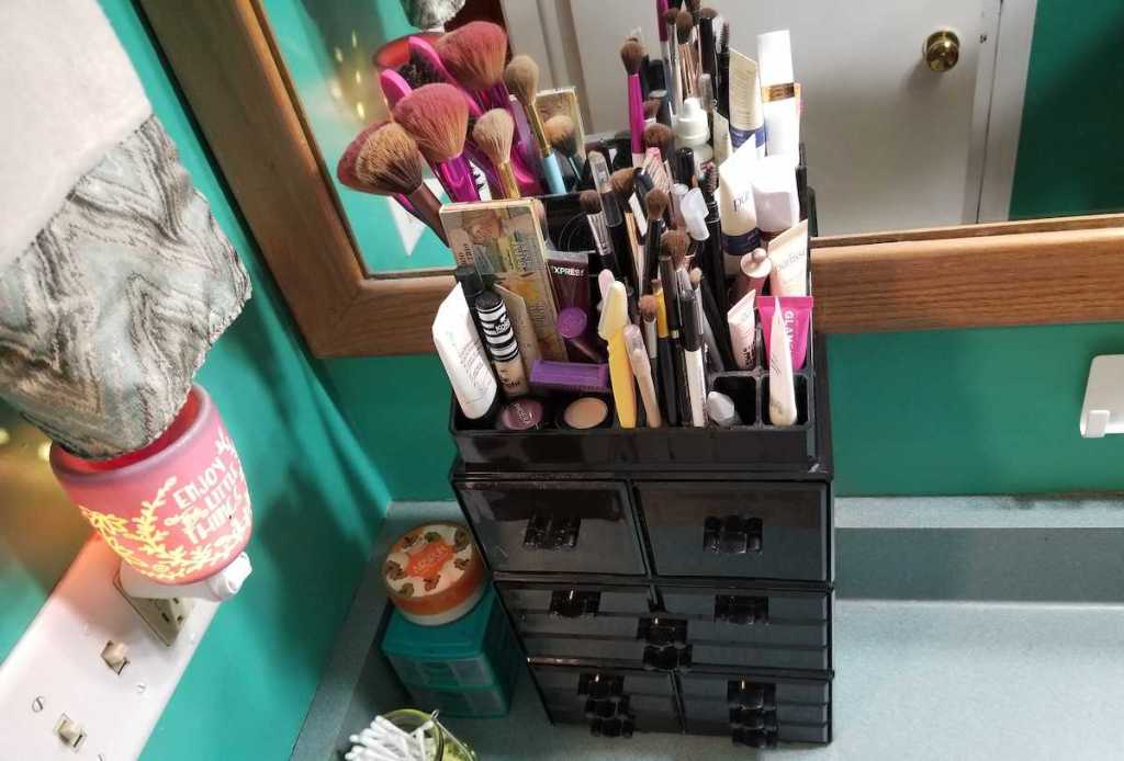Various cosmetics and make up brushes in black tiered drawer organizer