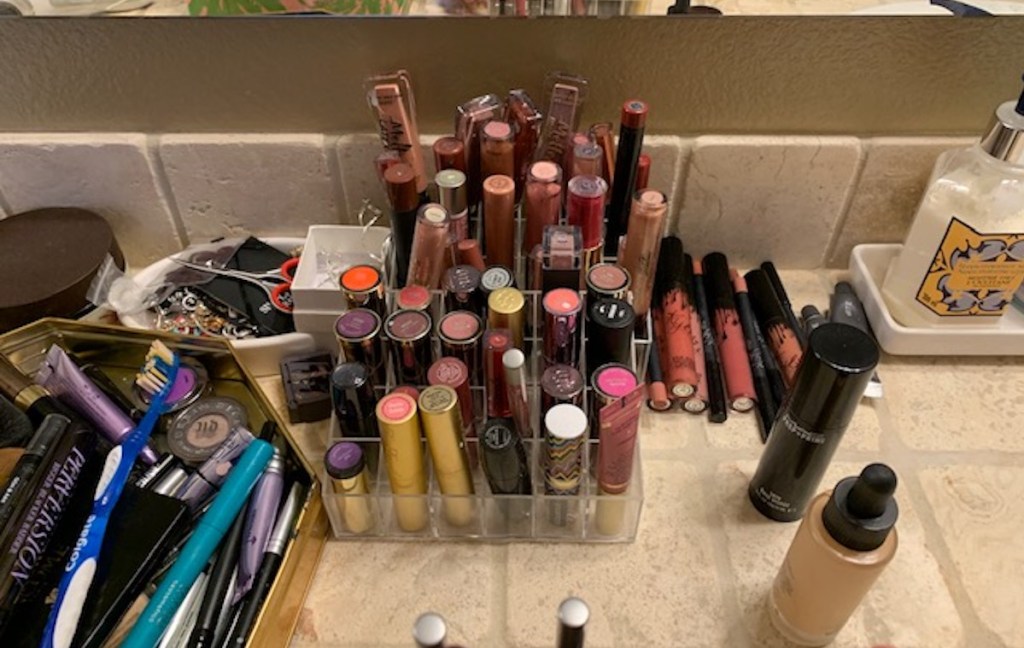 tons of various lip gloss and lipsticks in clear tiered organizer on counter