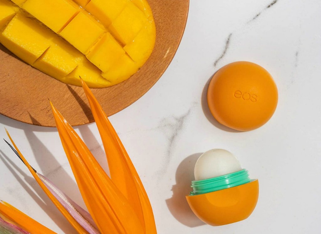 eos mango lip balm opened next to a sliced mango