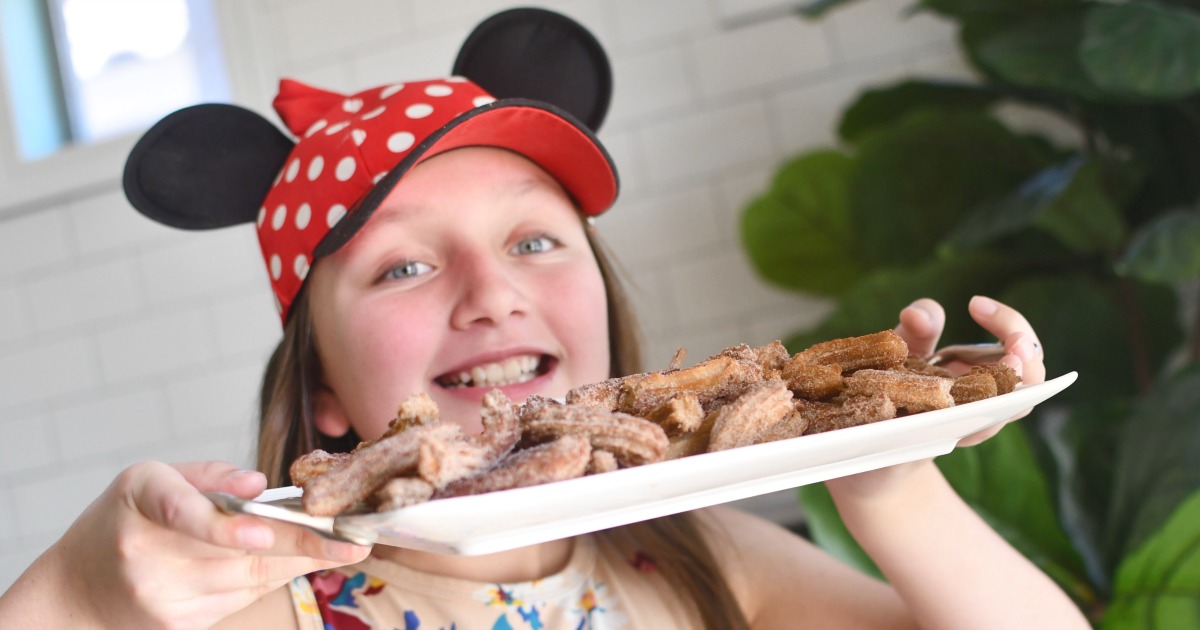 girl in mouse ears holding tray of churros