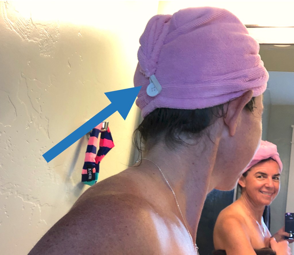 woman wearing pink hair towel looking in mirror smiling