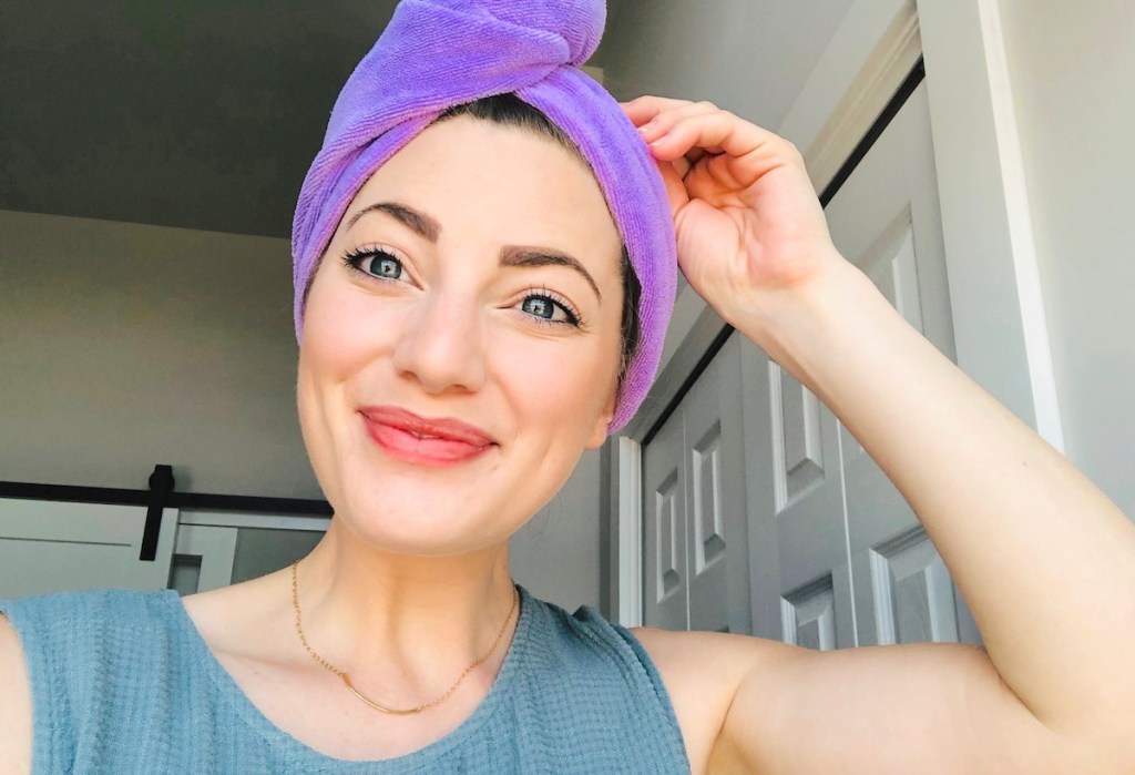 woman smiling with hand on head with purple hair towel