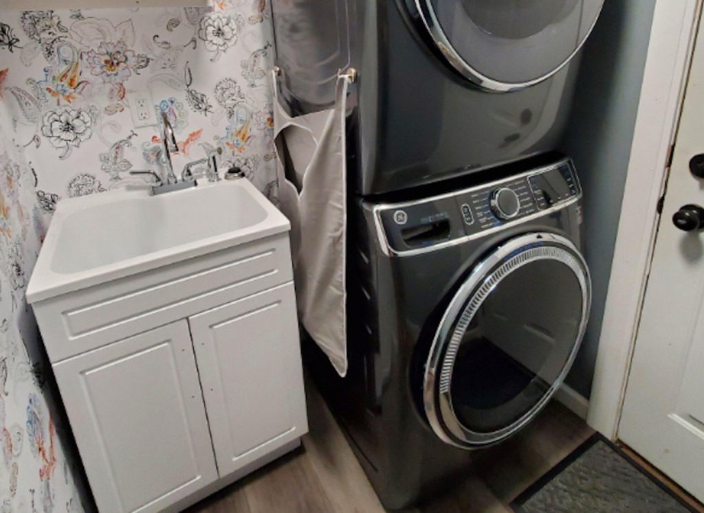 stacked dark gray laundry appliances in laundry room with hanging hamper