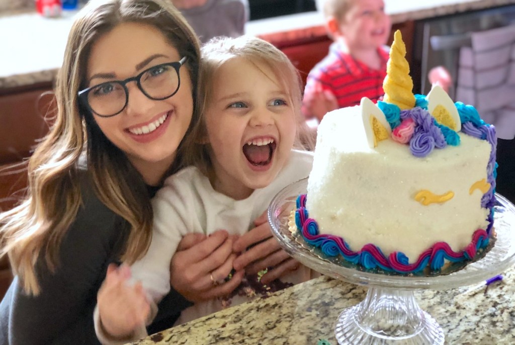 woman hugging happy girl laughing in front of birthday cake