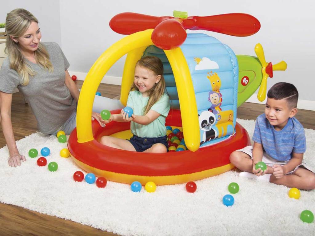 mom playing with kids in a helicopter ball pit