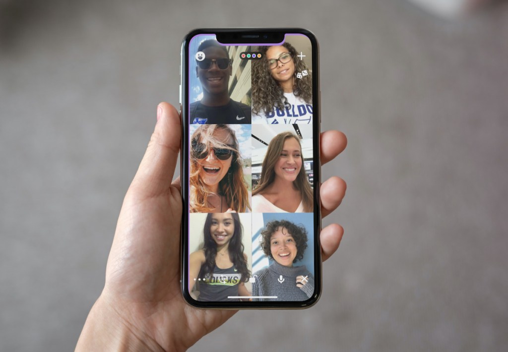 hand holding phone with multiple facetime people on screen