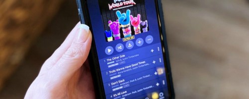 woman's hand holding an iPhone with Amazon Music app open to Trolls soundtrack