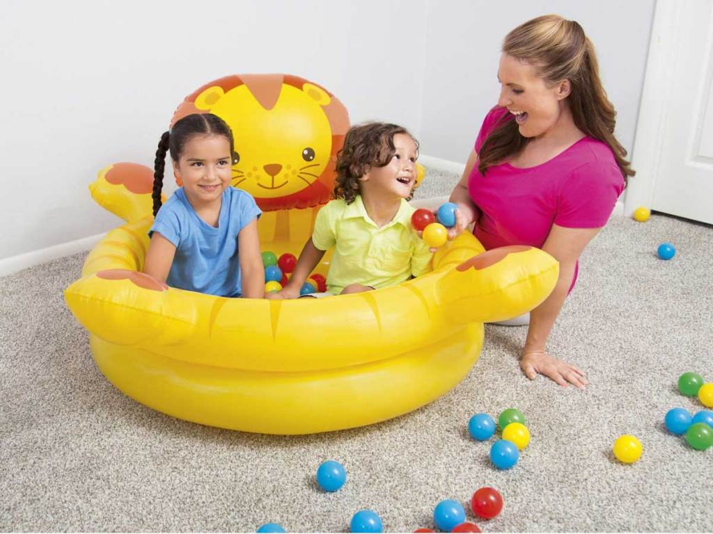 mom playing with kids in a lion ball pit