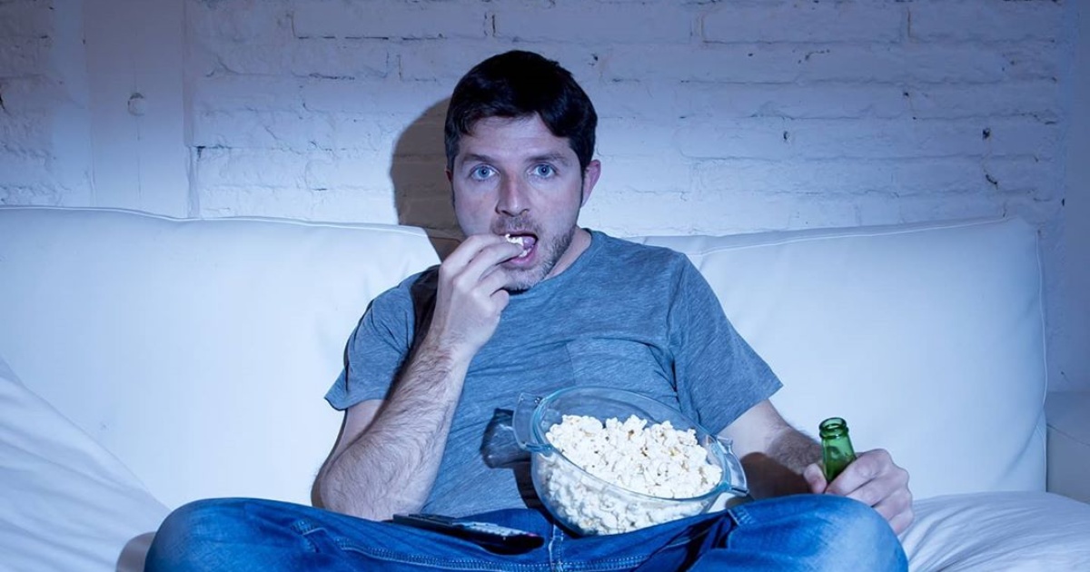 man eating popcorn in dark room