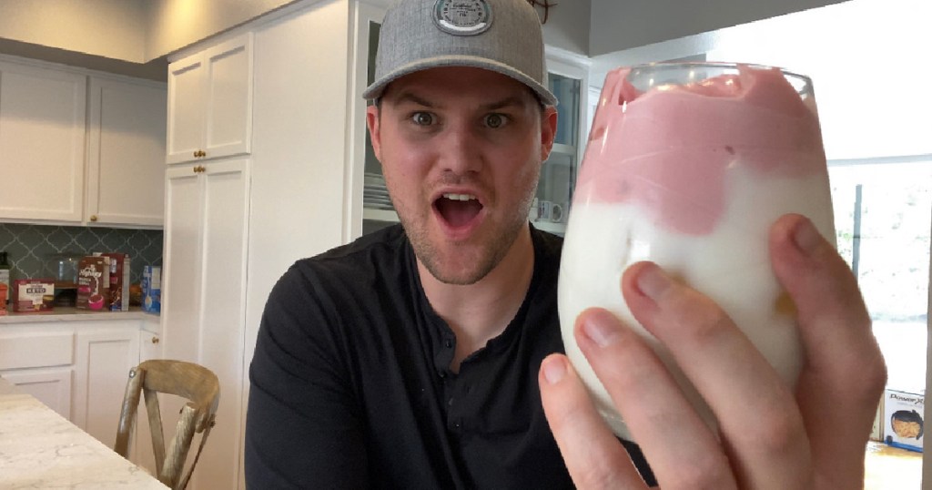 man holding up strawberry milk glass 