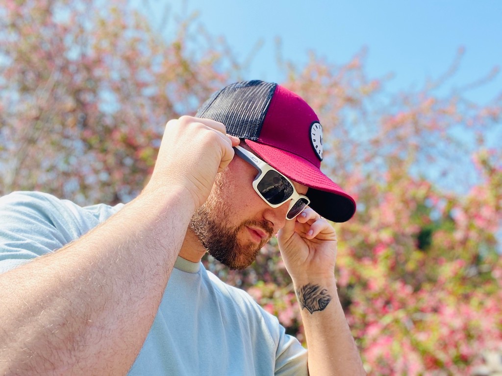 man wearing hat putting on Oakley sunglasses