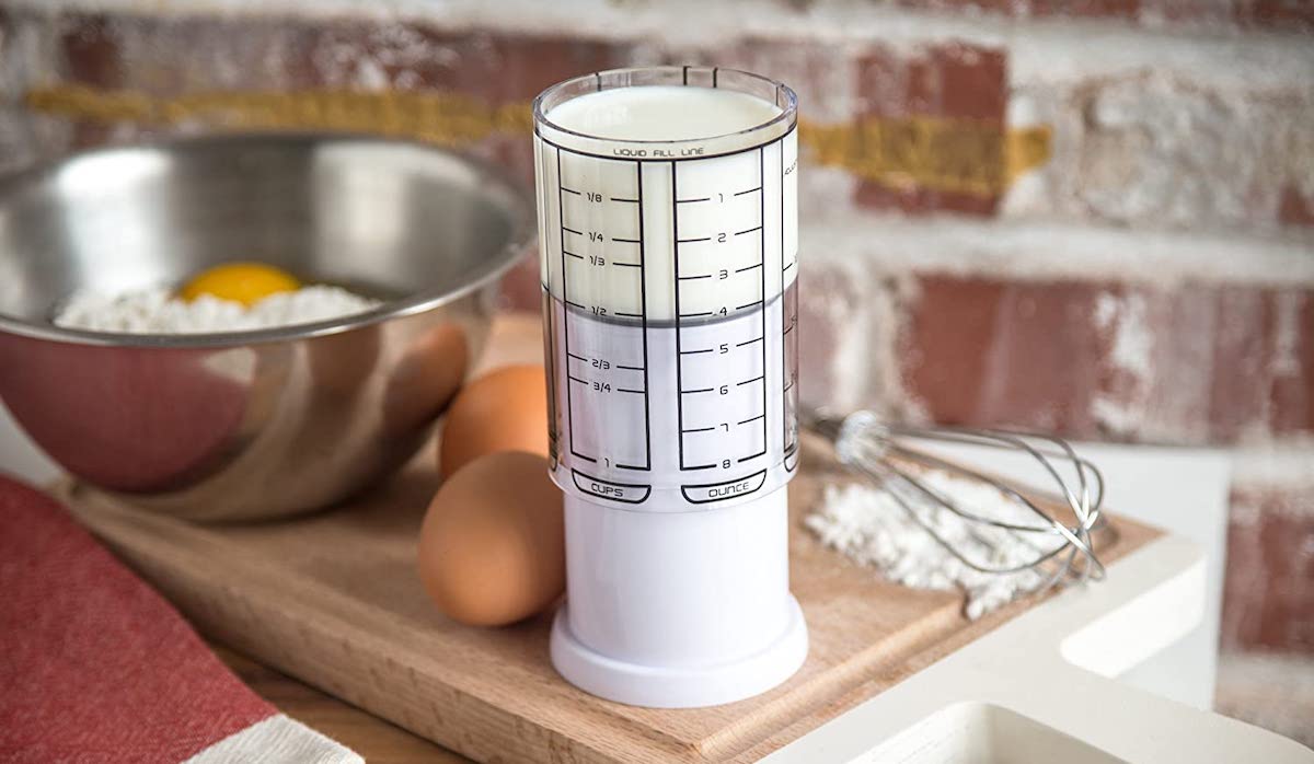 best kitchen gadgets - all in one measuring cup sitting on cutting board with eggs and stainless steel mixing bowl 