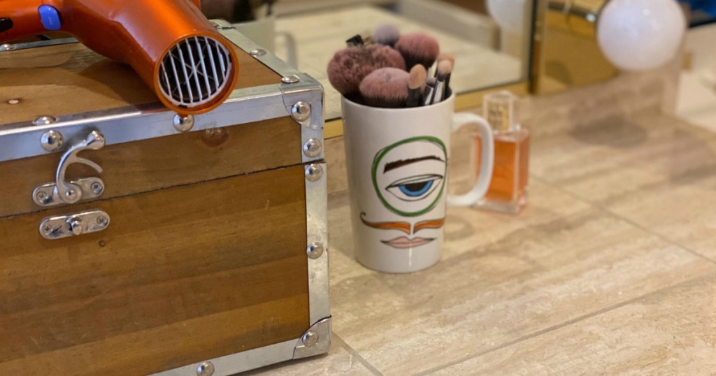 bathroom counter with mug with makeup brushes and storage chest