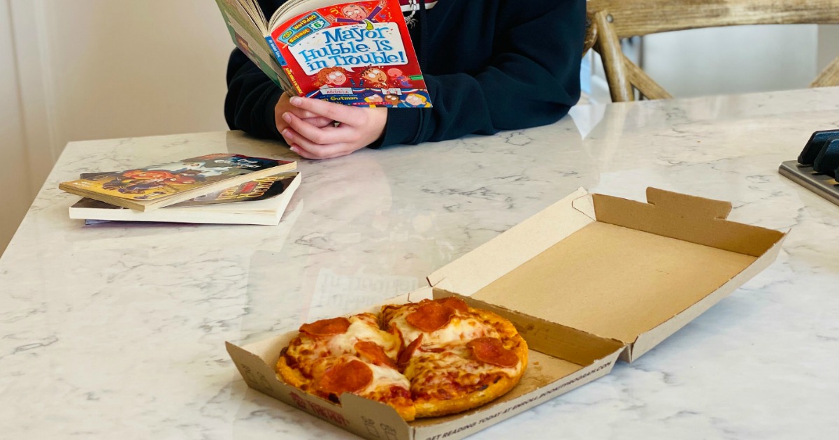 reading book with personal pan pizza on kitchen counter 