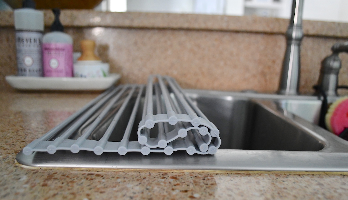 sink with silicone roll up drying rack over top