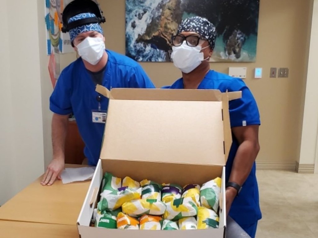 Health care workers holding a box of Subway subs