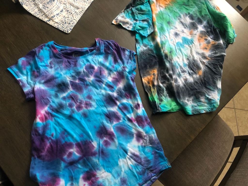 two different colored tie dye shirts on table
