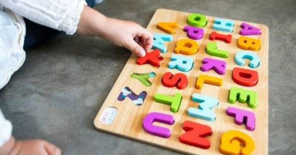 kids hand putting letters in abc puzzle