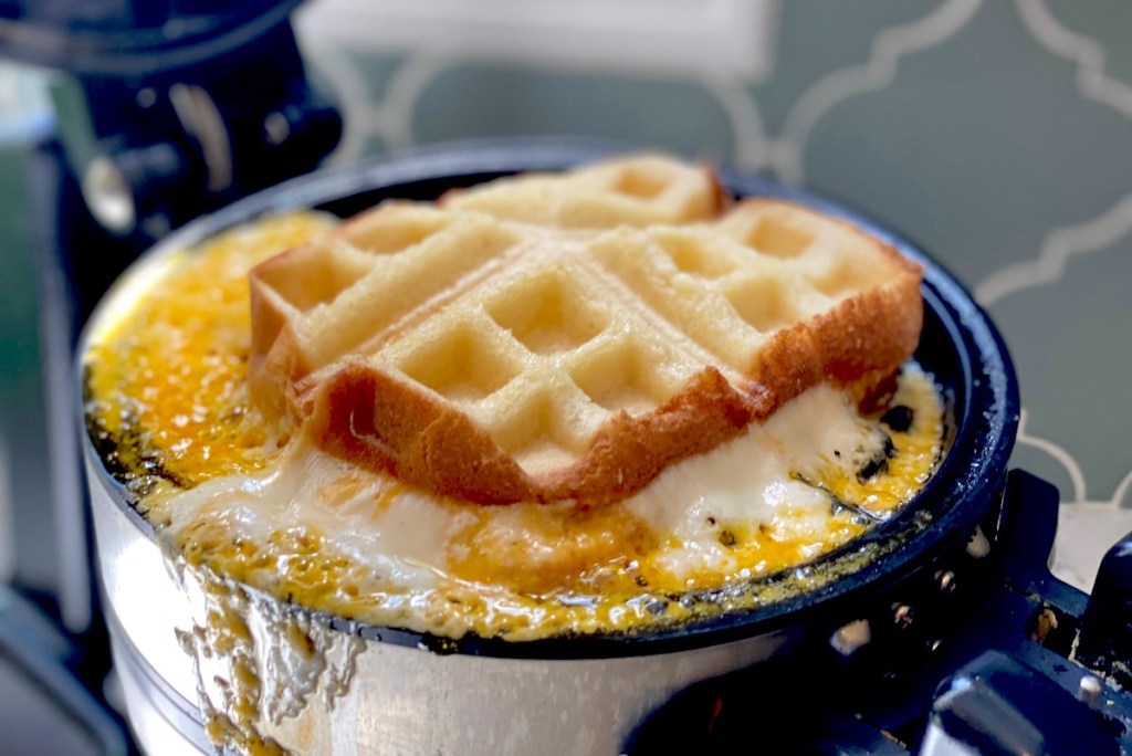 waffle maker with bread and cheese cooking in it