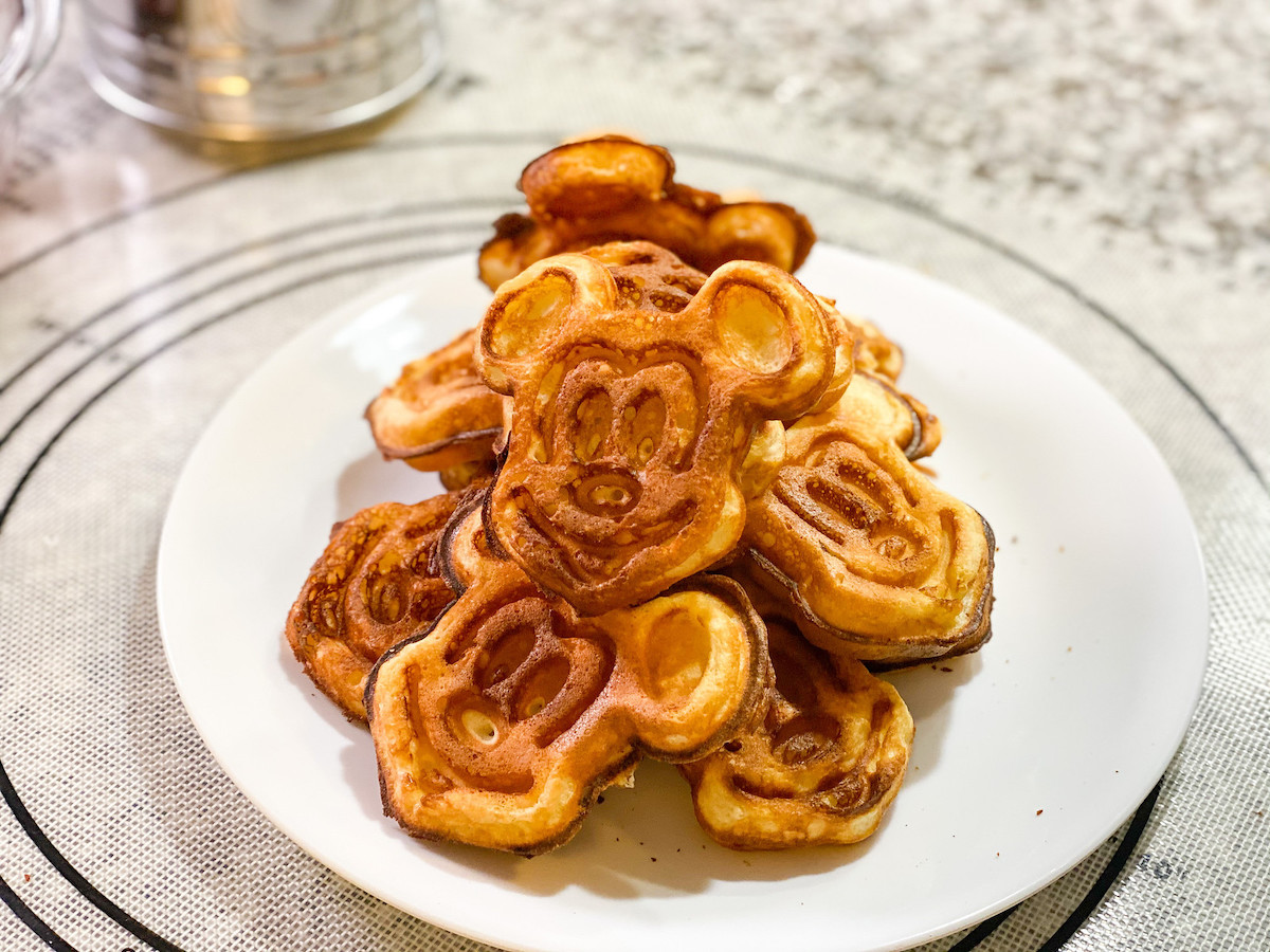 Tons of Mickey Mouse shaped waffles laying on white plates