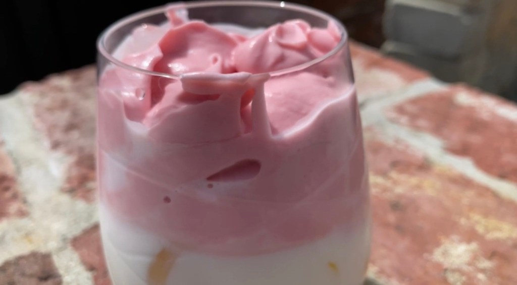 glass with pink whipped strawberry milk drink inside