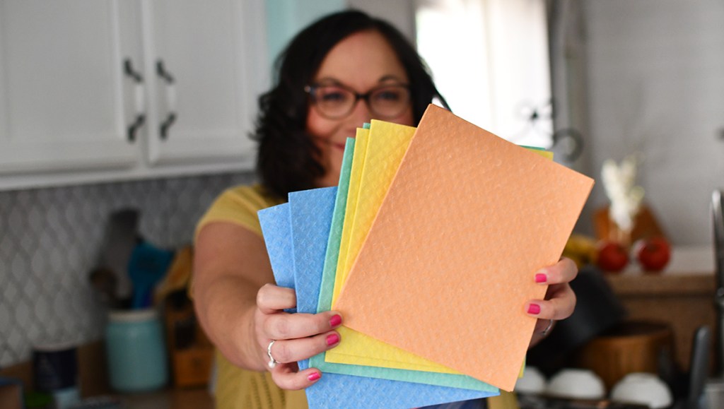woman holding various colors of Swedish dishcloths
