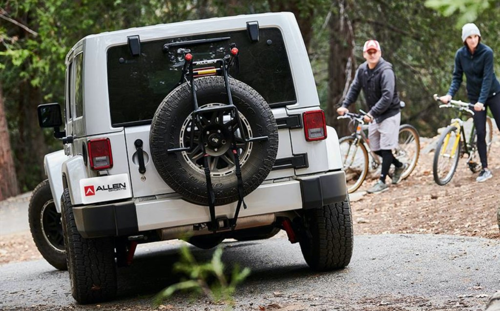 black spare tire bike rack on silver Jeep with two men walking bikes