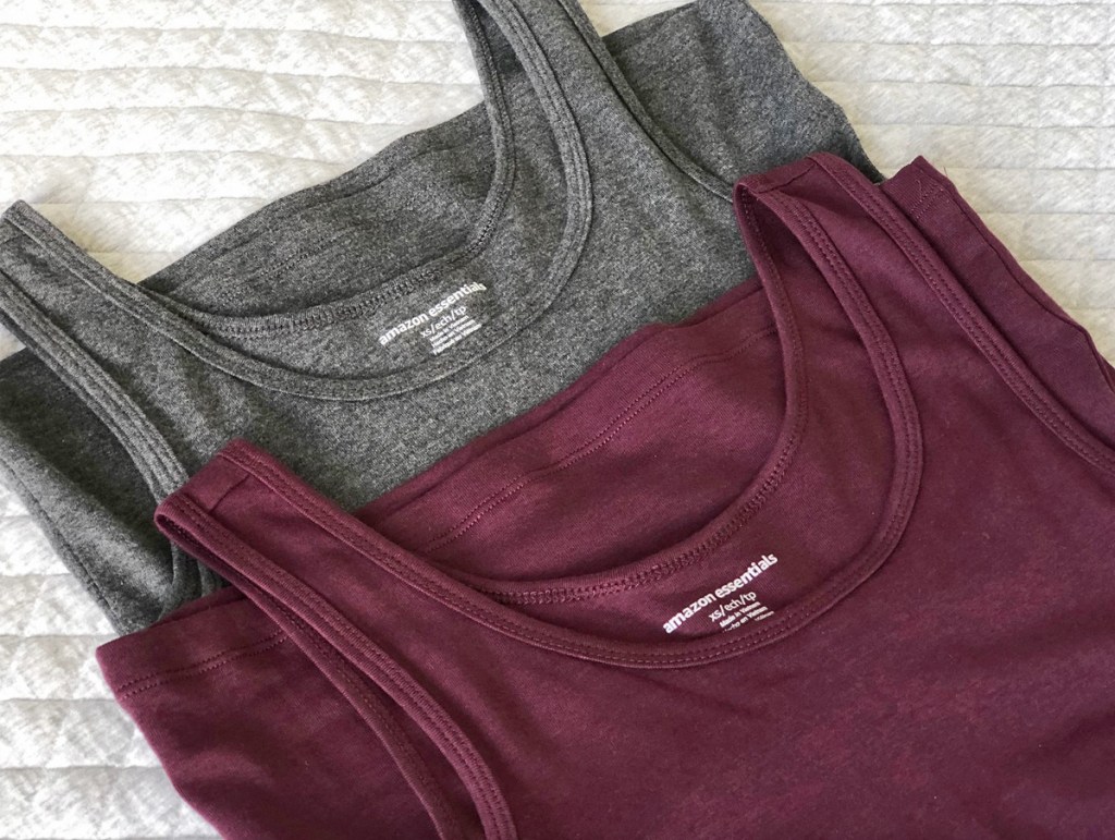 two amazon essentials brand tank tops in grey and maroon laying on bed